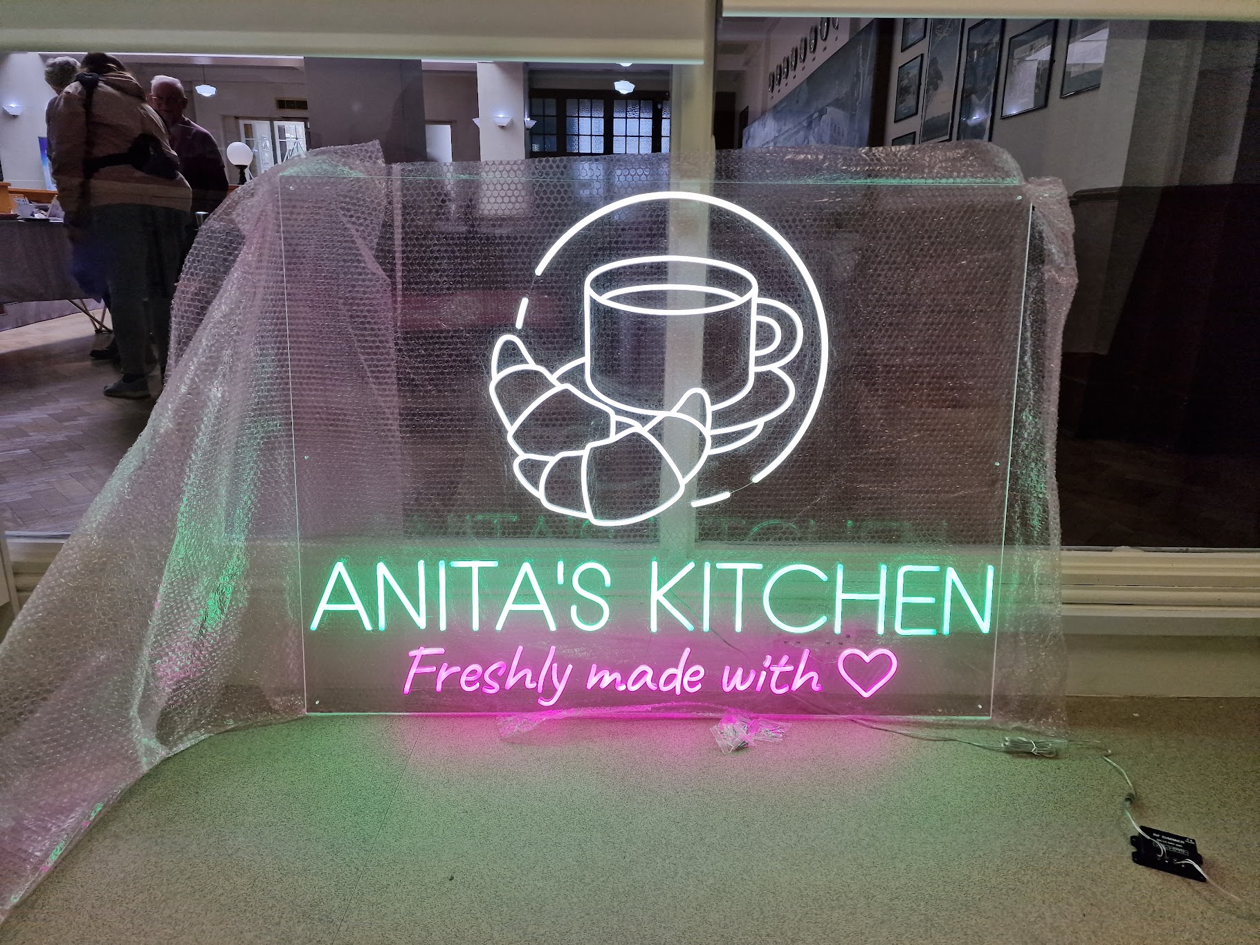 The Anita's Kitchen illuminated sign arriving wrapped for installation